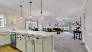 A spacious kitchen with a large island, light-colored cabinets, and pendant lighting. - Elegant 3BR Condo: Magnolia North 101 (Myrtle Beach)