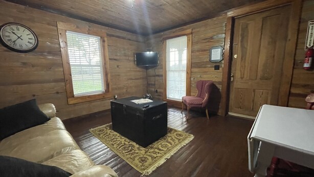 A wooden interior with a leather sofa, a small table, a television, and a door. - Row Cottages Redbud Cottage (Hartsfield)