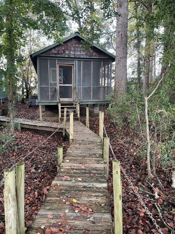 A wooden cabin with a porch and a wooden staircase leading up to it.
