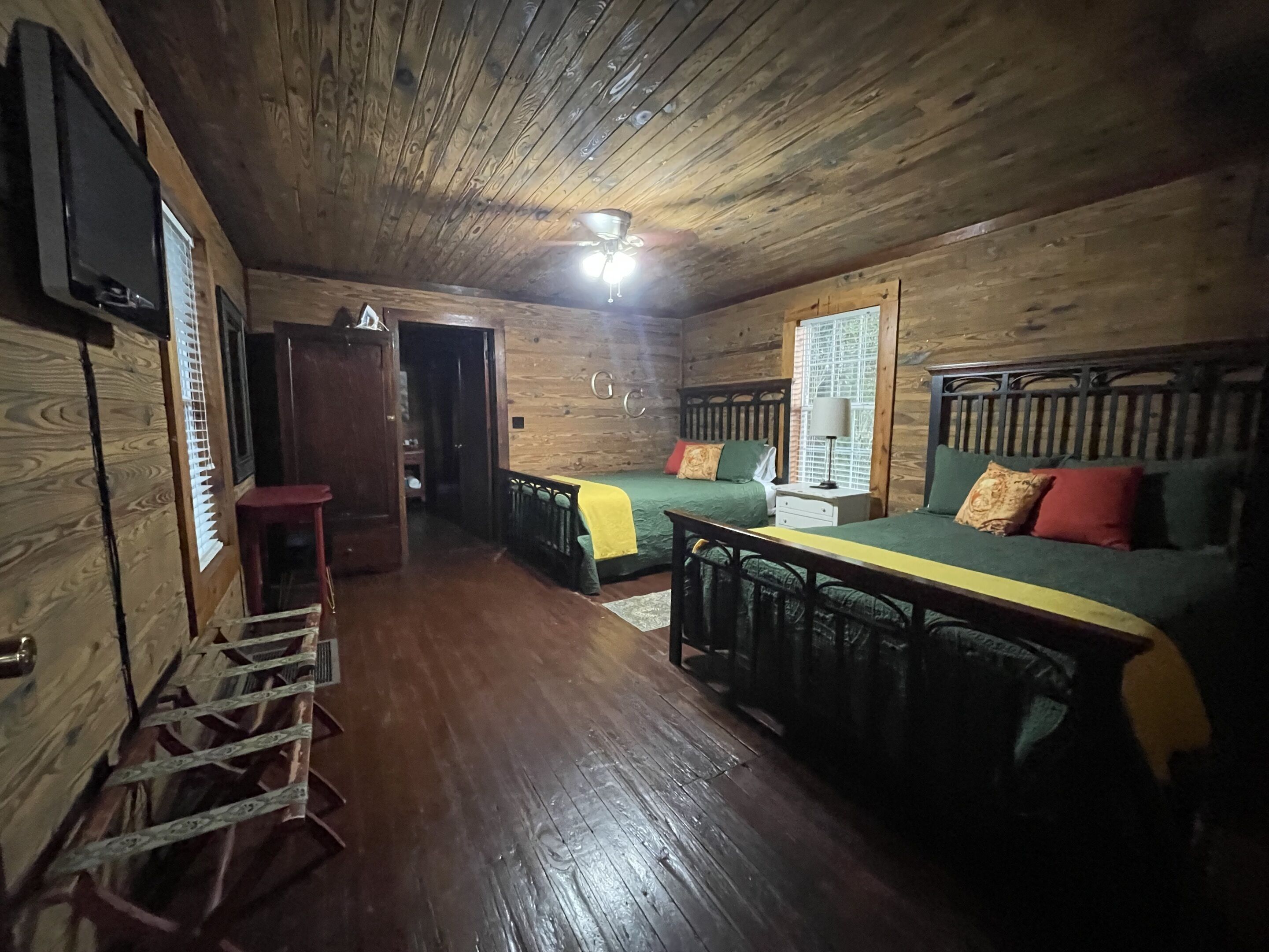 L’intérieur d’un chalet en bois comprend un lit, un canapé, une table et un téléviseur fixé au mur.