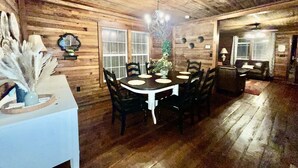 Ein Holzinterieur mit einem runden Esstisch, Stühlen und einem weißen Schrank.
