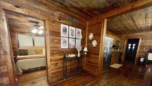 Un intérieur en bois comprenant un lit, une console avec une lampe et un réfrigérateur.