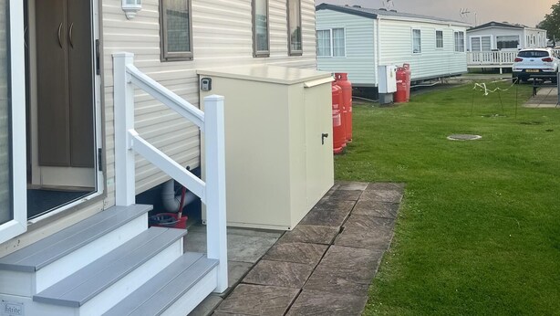 Una hilera de casas móviles con un patio césped y un arcoíris en el cielo.