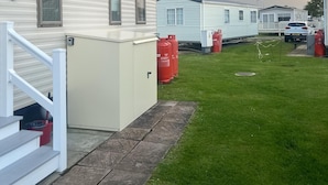 Una hilera de casas móviles con un patio cubierto de césped y un arcoíris al fondo.