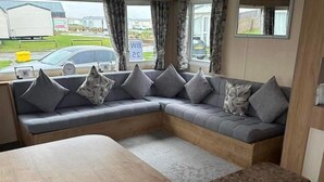Un interior acogedor con un sofá curvo, una mesa de madera y una ventana con cortinas.