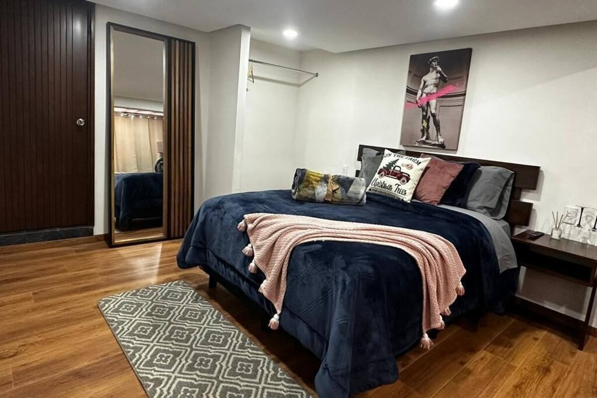 Une chambre à coucher avec un lit, une table de chevet, un miroir et une porte.