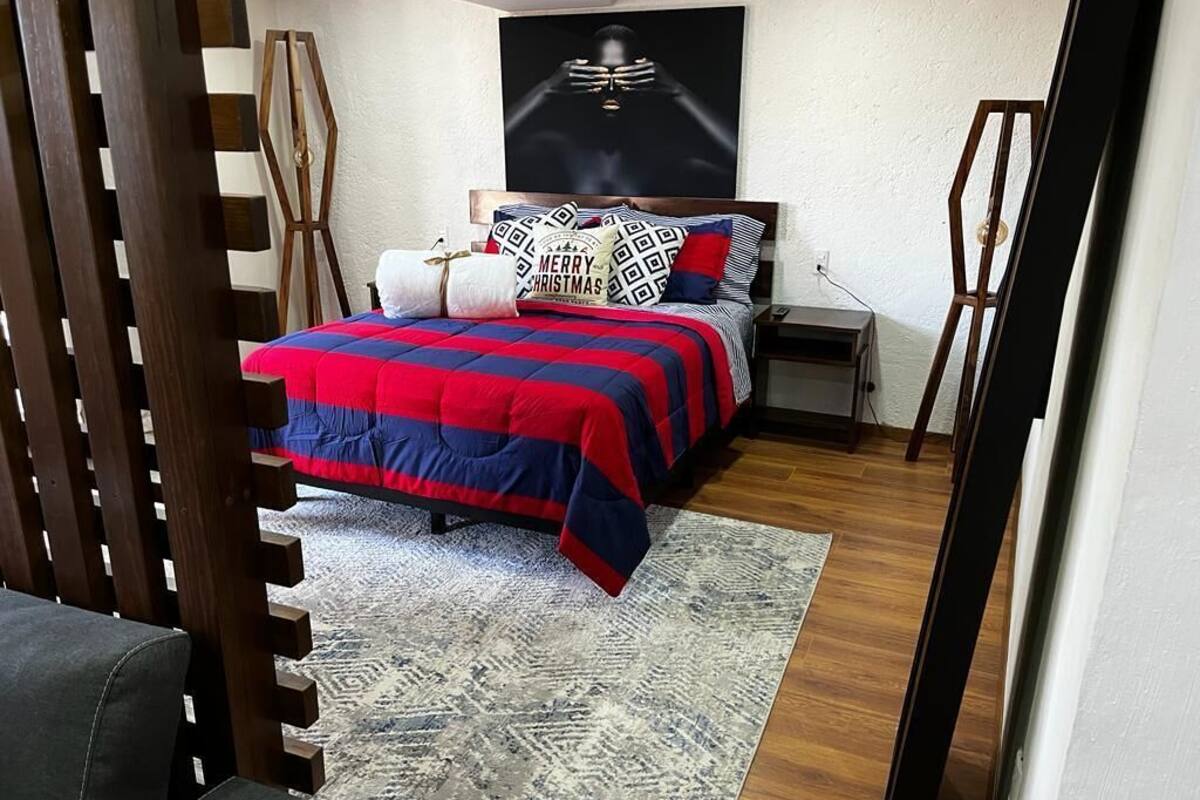 Une chambre à coucher avec un lit, une table de chevet, une échelle en bois et une œuvre d’art accrochée au mur.