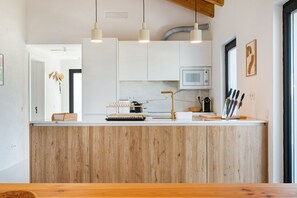 Una cocina moderna con una isla de madera, armarios blancos e iluminación colgante.
