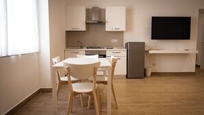 Una cocina moderna con armarios blancos, estufa integrada y televisor de pantalla plana sobre la encimera.