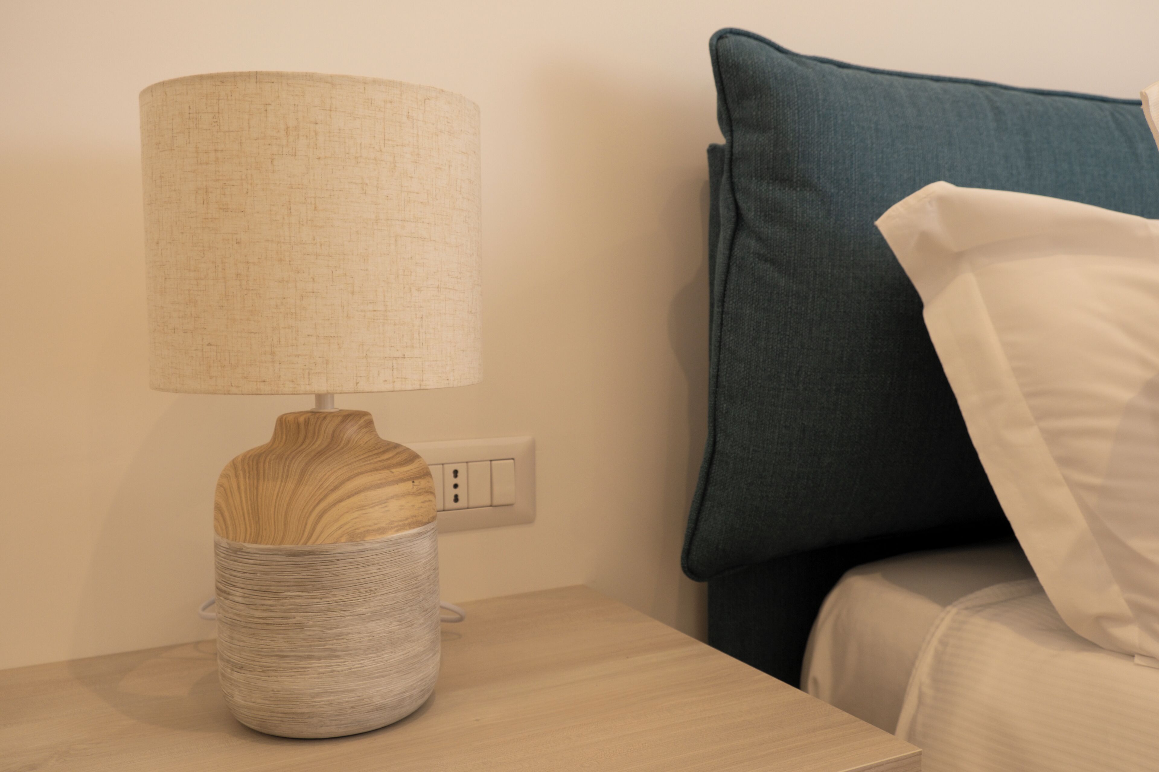 A bedside table with a lamp and a decorative vase.