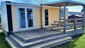 Una casa móvil con un porche cubierto, puerta corrediza de vidrio y una mesa de picnic.