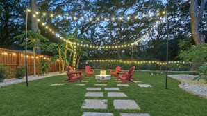 A backyard with a fire pit, red chairs, and string lights. - Palm Haus • Heated Pool • Near Beach • Game Room • Volleyball • Gas Fire Pit (Palm Harbor)
