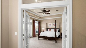 Camera da letto con letto a baldacchino, ventola a soffitto e vista sull'esterno tramite una porta.