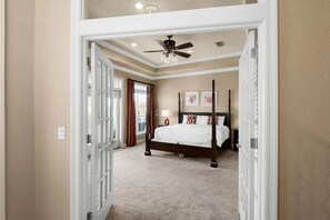 A bedroom with a four-poster bed, a ceiling fan, and a view of the outside through a door. - Summer Blast: Private Beach Access! (Destin)
