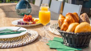 Desayuno con vaso de jugo de naranja, croissants y una fuente de fruta.