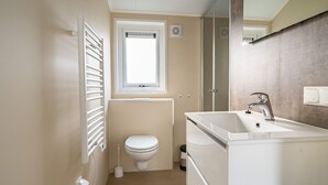 Un baño con inodoro, ventana, lavabo y espejo.