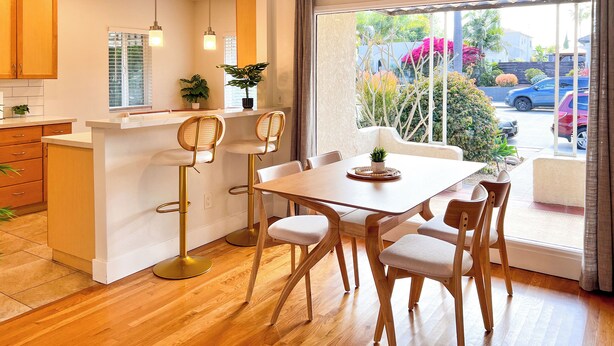 Una cocina moderna con armarios de madera, una isla central y un comedor con mesa y sillas.