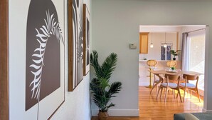 Una sala de estar moderna con piso de madera, un comedor con mesa y sillas de madera, y una cocina visible al fondo.