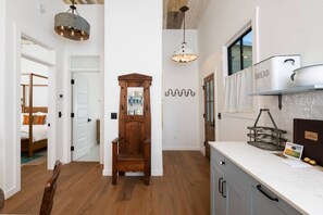 Una cucina moderna con un armadietto in legno, un lampadario a sospensione e un porta pane sul bancone.
