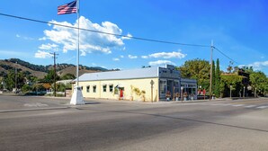 A two-story building with a flat roof, a flagpole with an American flag, and a clear blue sky. - Jasmine residence, located downtown between the Union Hotel & Bells restaurant. (Los Alamos)