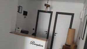 Een receptiezone met een marmeren vloer, een receptiebalie met de tekst 'Reception' en een houten stoel.
