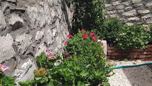 Een tuin met een stenen muur, bloeiende planten en een grindpad.
