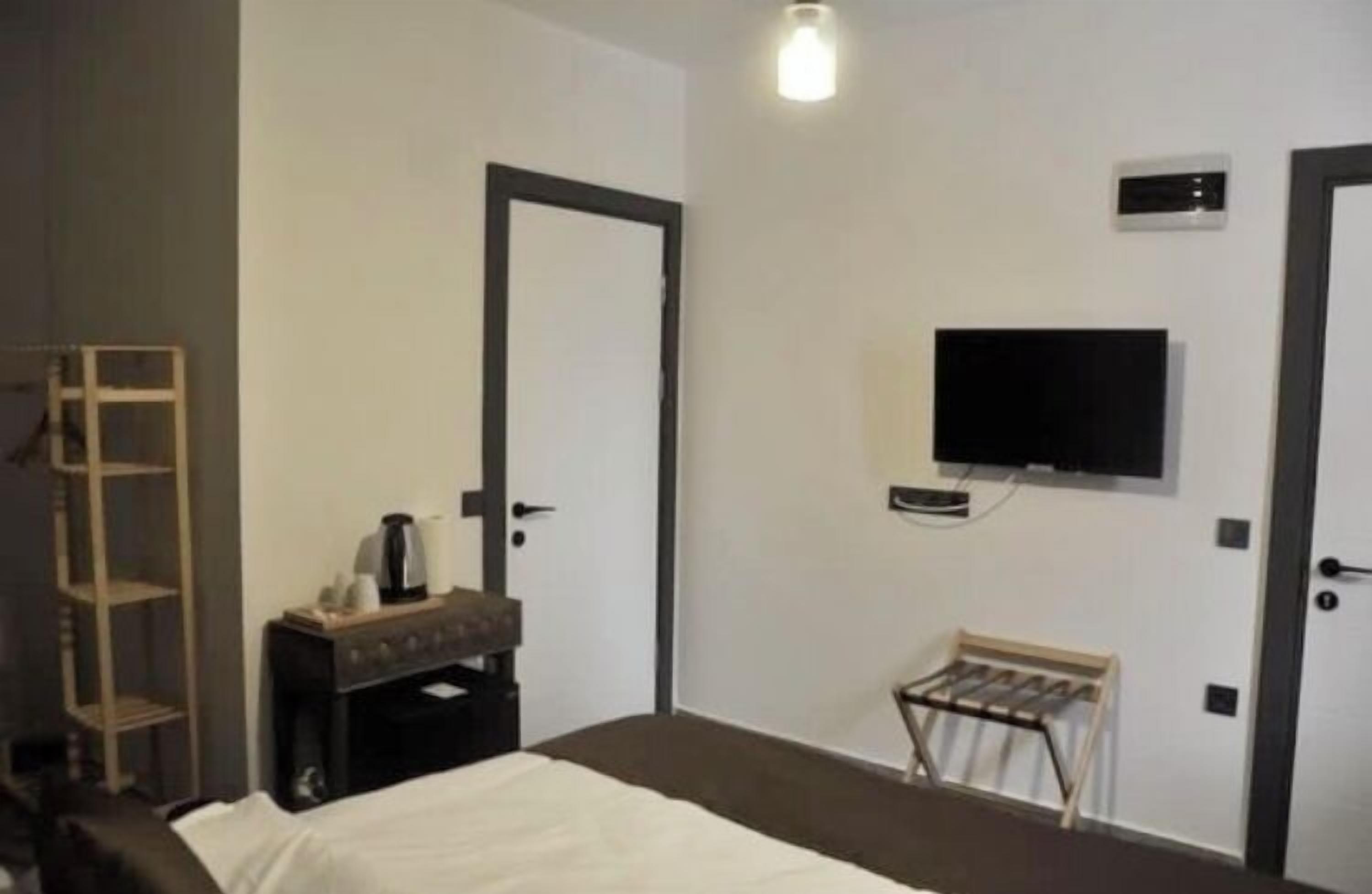 Hotelkamer met een bed, een tv aan de muur, een klein tafeltje met een waterkoker en een plank.