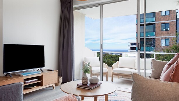 A modern living room with a flat-screen TV, a wooden coffee table, and a sofa.