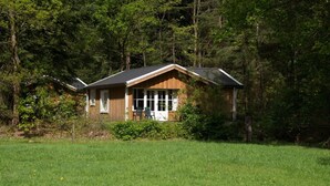 A cabin with a sloped roof, large windows, and a porch with a chair. - Cozy Chalet Near a National Park (Ruinen)