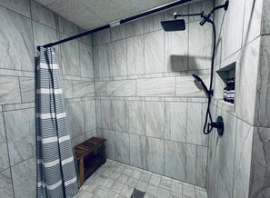 Un espace douche doté d’un pommeau de douche incurvé, d’un pommeau de douche à main et d’un rideau de douche.