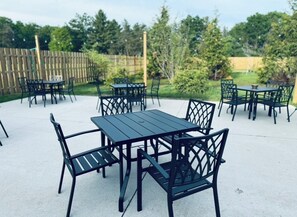 Un espace extérieur aménagé en terrasse, avec plusieurs tables et chaises.