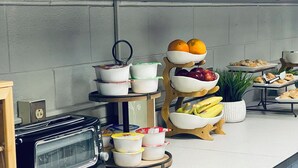A kitchen counter with a toaster, a fruit bowl, and a tray of pastries.