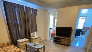 Un salon avec un canapé, une table basse, un téléviseur et un radiateur.