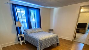 Une chambre à coucher avec un lit, une table de chevet, une lampe et une chaise.