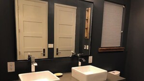 A bathroom with two white sinks, a large mirror, a toilet, and a window with blinds. - Beautiful Cottage, hot tub, in great neighborhood (San Francisco)