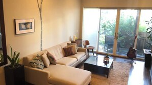 A living room with a sofa, coffee table, and a guitar. - Beautiful Cottage, hot tub, in great neighborhood (San Francisco)