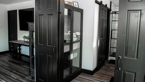 A hallway with a dark wooden floor, a glass-fronted cabinet, and a black door. - Beautiful, Spacious 4-BR  home in Thackerville, OK near Winstar World Casino (Thackerville)