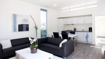 Relax in this stylish living room with a sofa, coffee table, and dining area, offering a view of the outdoors.