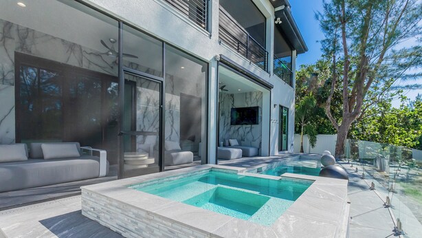 A modern outdoor pool area with a glass-enclosed patio, a built-in hot tub, and a seating area with a sofa and chairs. - 5bdr/5.5ba Modern Oasis with outdoor Gym, Cold Plunge, Heated Pool & Jacuzzi (Naples)