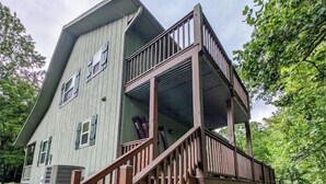 A two-story house with a wooden deck and a covered porch. - Charming and Cozy River House (Murphy)