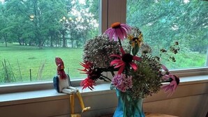 A vase with flowers on a wooden table by a window. - Charming and Cozy River House (Murphy)