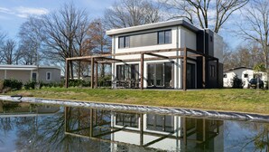 A modern two-story house with a covered patio and a pond in front. - Luxury Villa With Dishwasher (Kerkdriel)