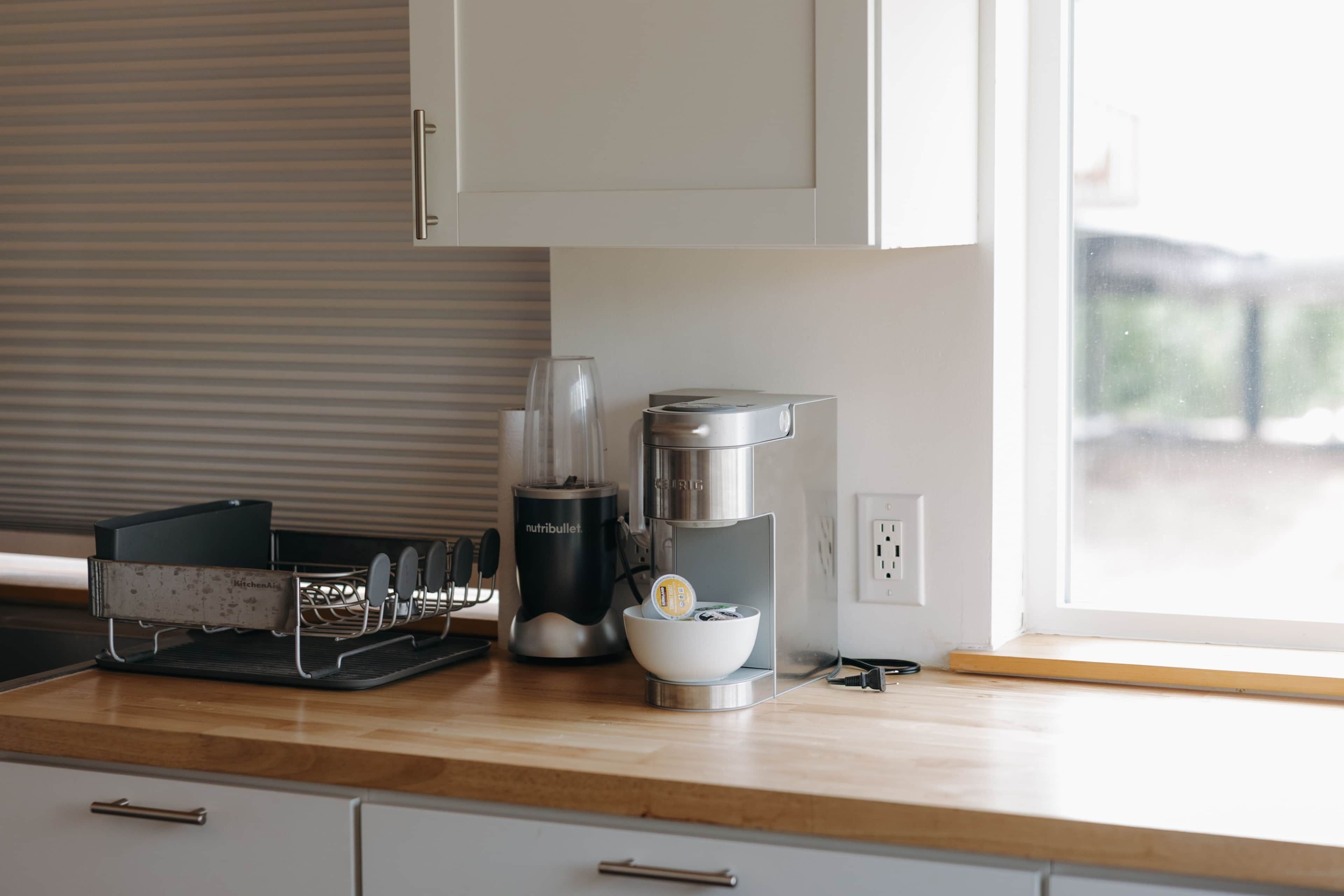 A kitchen with a coffee maker, a kettle, and a coffee grinder on the counter.