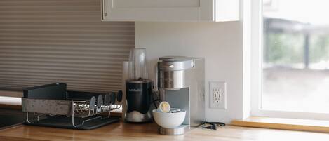 A kitchen with a coffee maker, a kettle, and a coffee grinder on the counter.