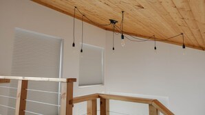 Ein Zimmer mit Holzbalken an der Decke, weißen Wänden und einem Holzbalkenlaufgeländer.