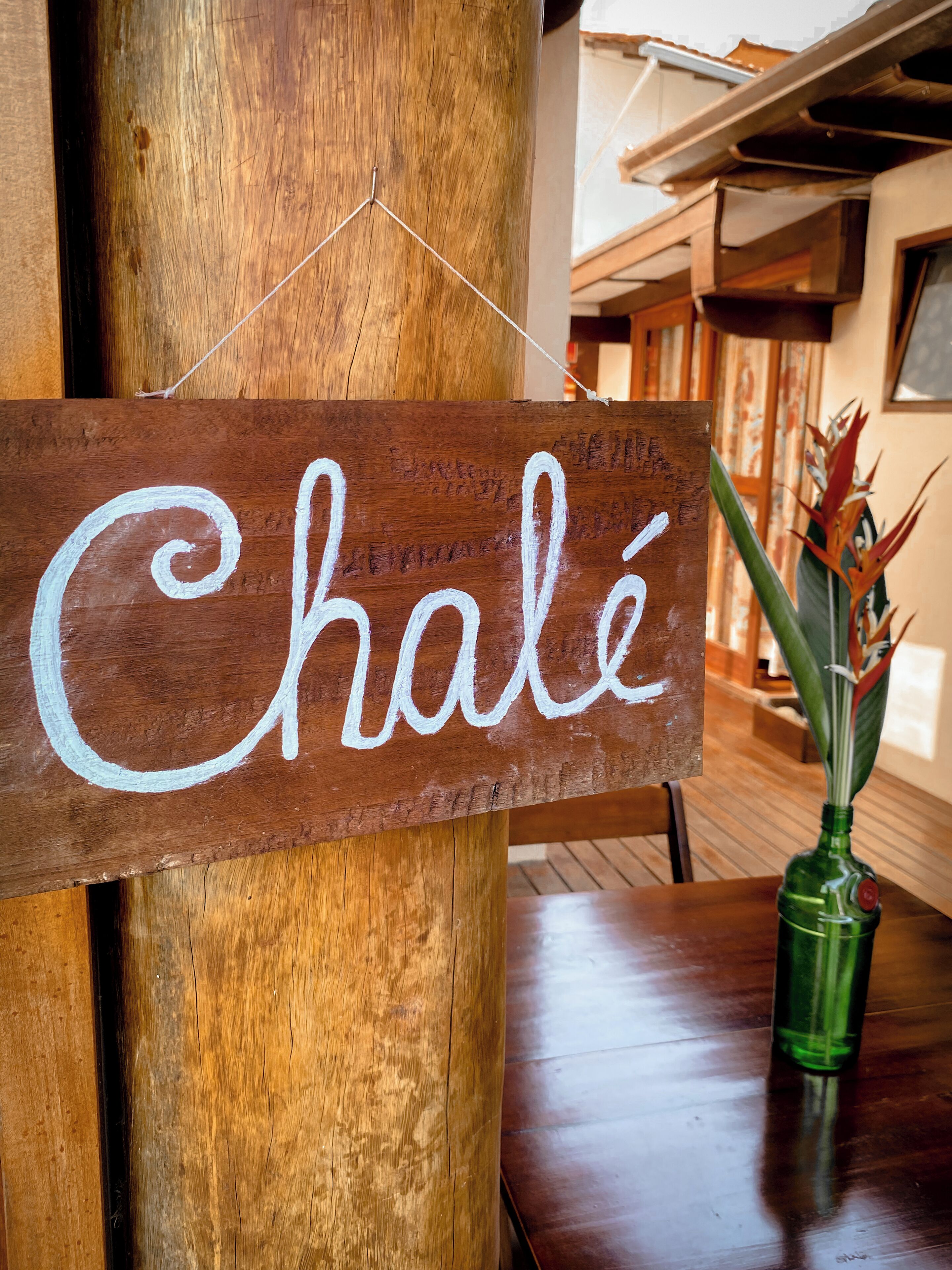 A wooden sign with the word "Chalet" written on it, hanging from a wooden beam.