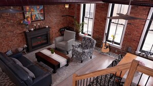 A cozy living room with a fireplace, comfortable seating, and large windows. - French Inn in Downtown Belleville ,  right above our charming French Bistro  (Belleville)