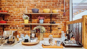 A kitchen with a brick wall, shelves with kitchenware, a coffee machine, and various containers. - French Inn in Downtown Belleville ,  right above our charming French Bistro  (Belleville)