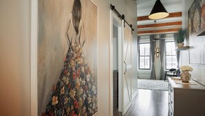 A hallway with a large floral painting, wooden flooring, and a modern pendant light. - French Inn in Downtown Belleville ,  right above our charming French Bistro  (Belleville)
