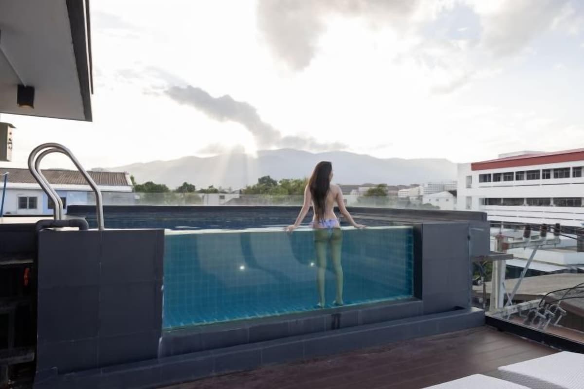 Une piscine sur le toit offrant une vue sur les bâtiments et les montagnes.